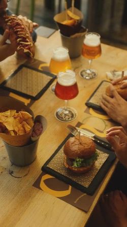 Craft beer and burgers served at Open Baladin Cuneo with chips and casual dining setup on wooden table.