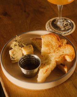 Toasted bread slices served with cheese and a small dipping sauce cup on a beige plate at Open Baladin Torino.