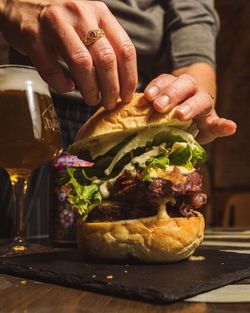 Hamburger con doppio strato di carne, lattuga e salsa, accompagnato da birra artigianale Baladin in bicchiere.