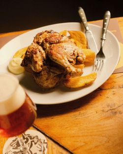 Roasted chicken with potato wedges and mayonnaise on a white plate, with a glass of craft beer at Open Baladin Roma.