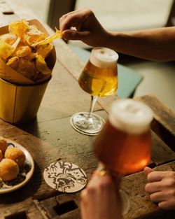 Birra artigianale servita in bicchieri di design con contorno di patatine e finger food su tavolo di legno.