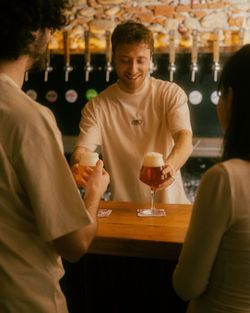 Persona che serve birra artigianale al bancone di Baladin Open Garden con rubinetti visibili sullo sfondo.