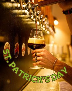 Versamento di birra artigianale scura da una leva in un bicchiere con schiuma densa in un bar.