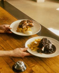 Due piatti con carne e contorni di patate sul tavolo di legno in Baladin Open Garden.