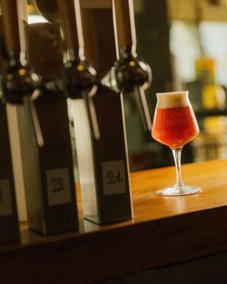 Verre de bière artisanale Baladin ambrée sur un comptoir en bois, avec plusieurs tireuses à bière en arrière-plan.