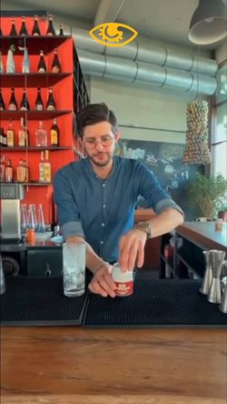 Bartender preparing a craft beer behind the bar at Open Baladin Torino with bottles displayed on red shelves.