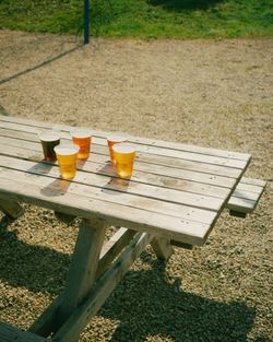 Cinq verres de bière artisanale aux couleurs variées posés sur une table en bois à l'extérieur.