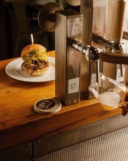 Hamburger auf weißem Teller neben Zapfhähnen mit Craft-Beer im Open Baladin Roma