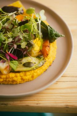 Colorful vegetable dish with leafy greens and pumpkin seeds on a beige plate at Baladin Open Garden.