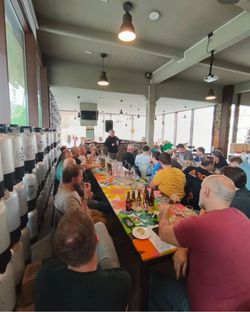 Group of people sitting at a long table inside Open Baladin Cuneo, enjoying craft beer and socializing.