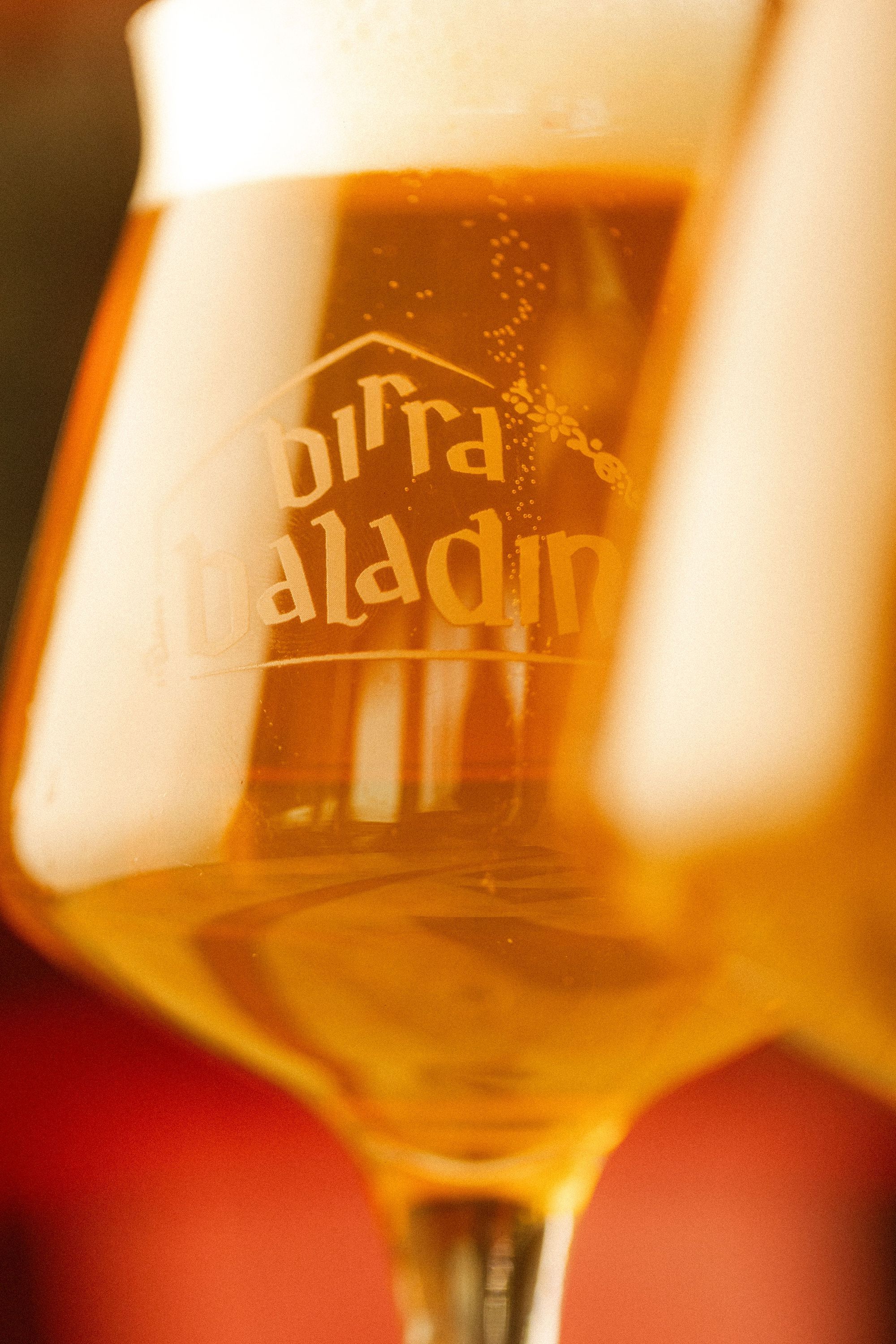 Verre de bière artisanale Birra Baladin avec mousse blanche dans un cadre chaleureux.