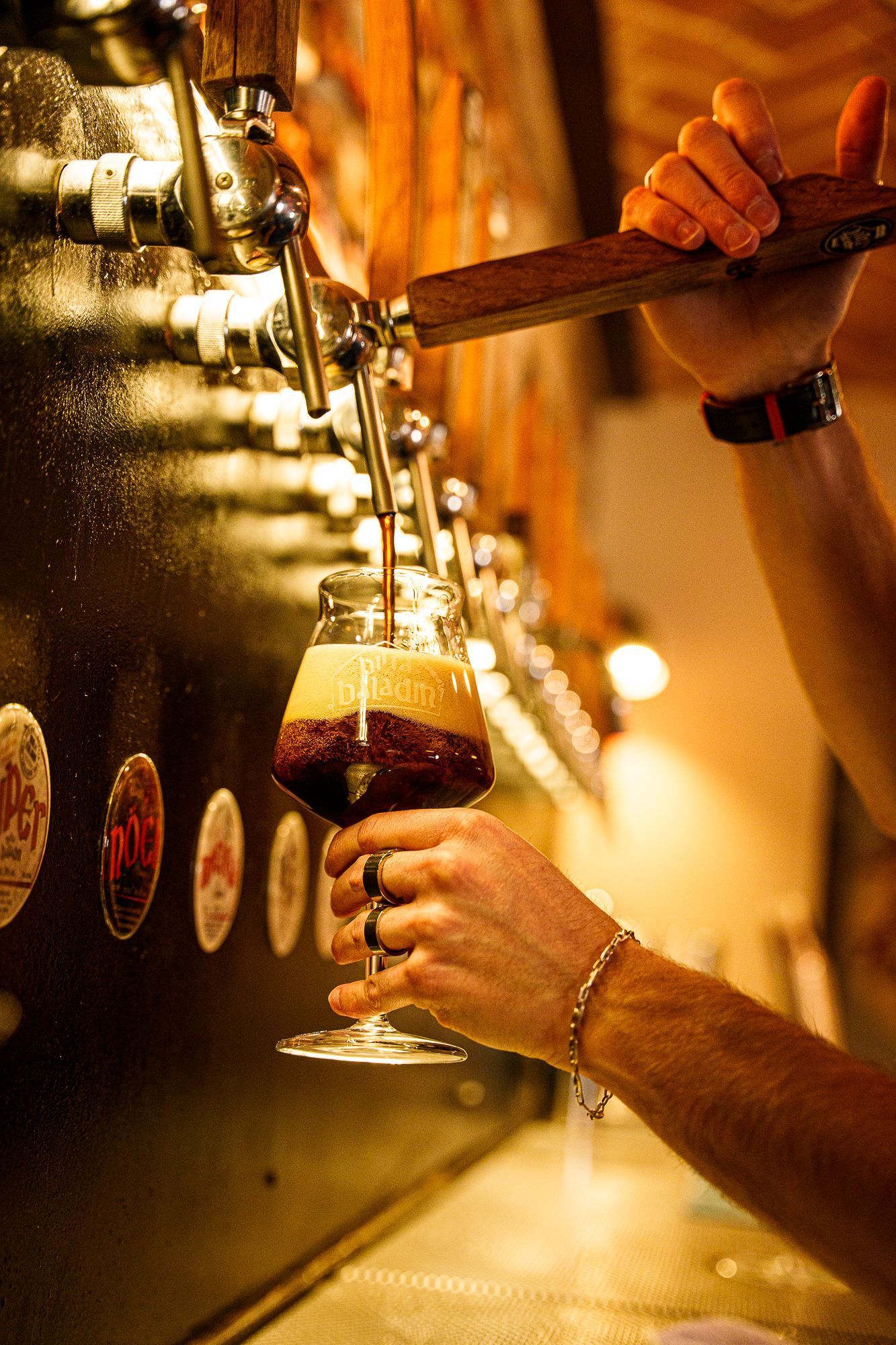 Un verre de bière artisanale Baladin est versé à partir d'un robinet en bois dans un bar avec plusieurs tireuses à bière.