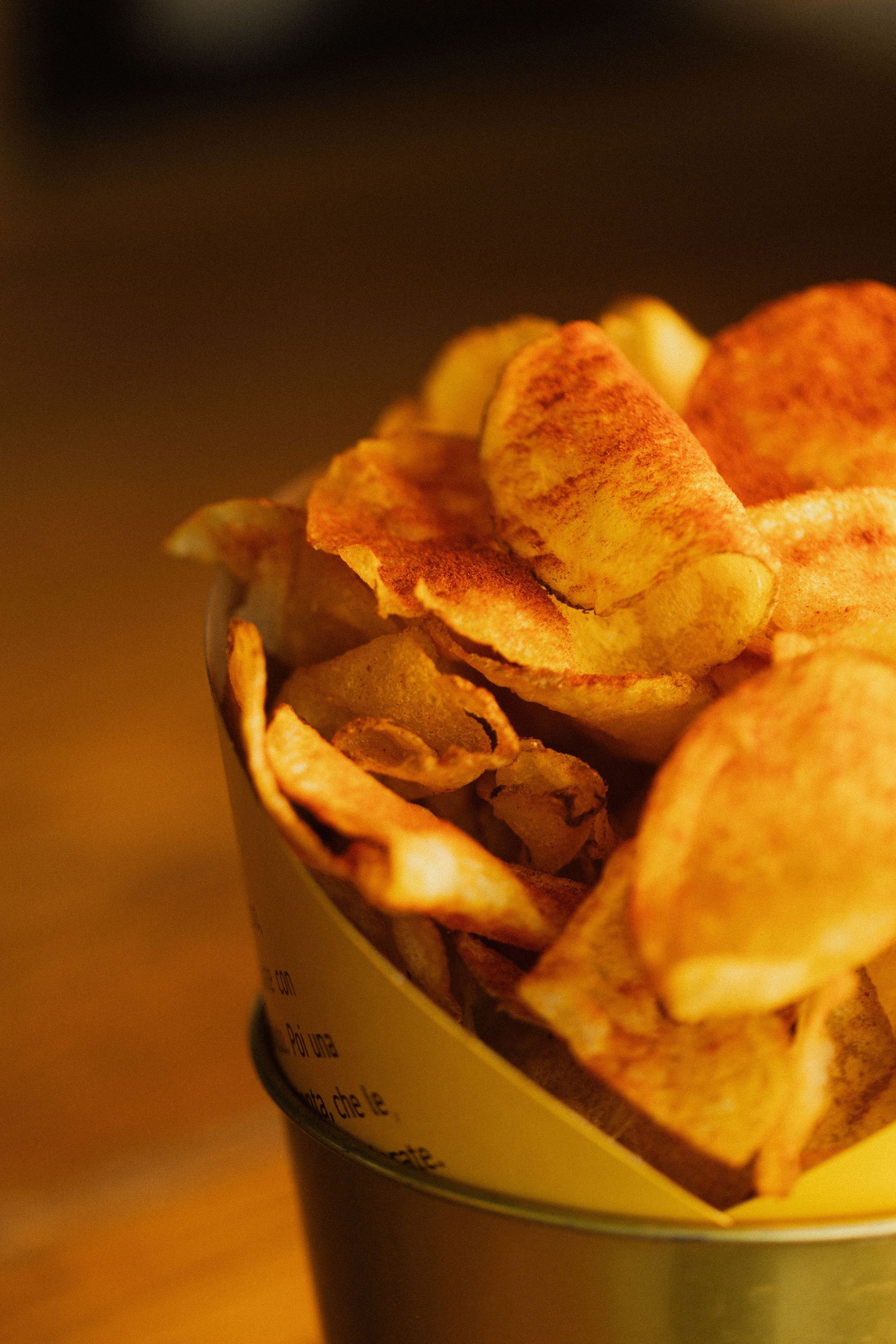 Close-up of crispy potato chips served in a yellow container at Open Baladin Cuneo.