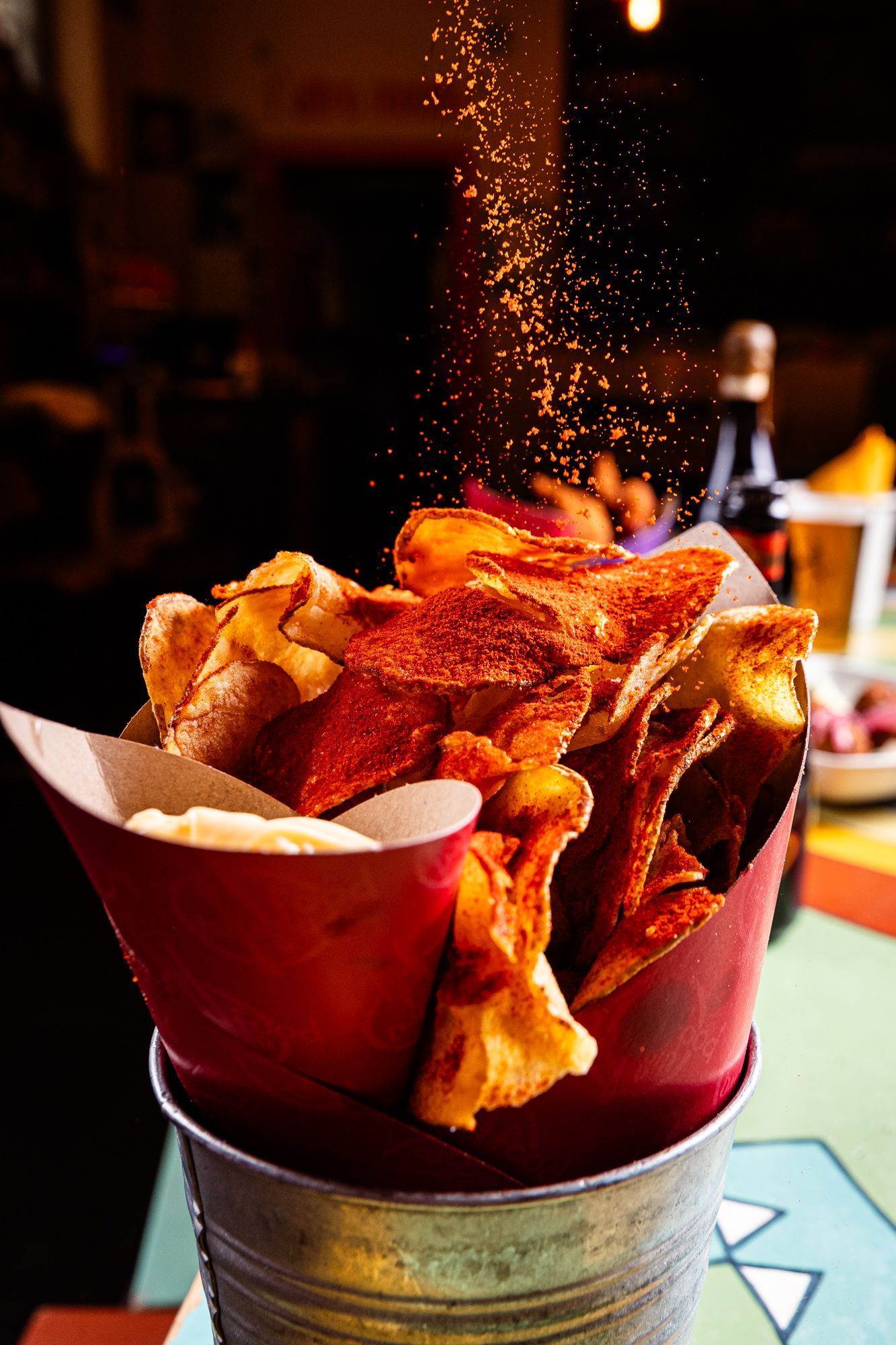 Chips épicées servies dans un pot métallique au restaurant Open Baladin Roma avec une ambiance chaleureuse en arrière-plan.
