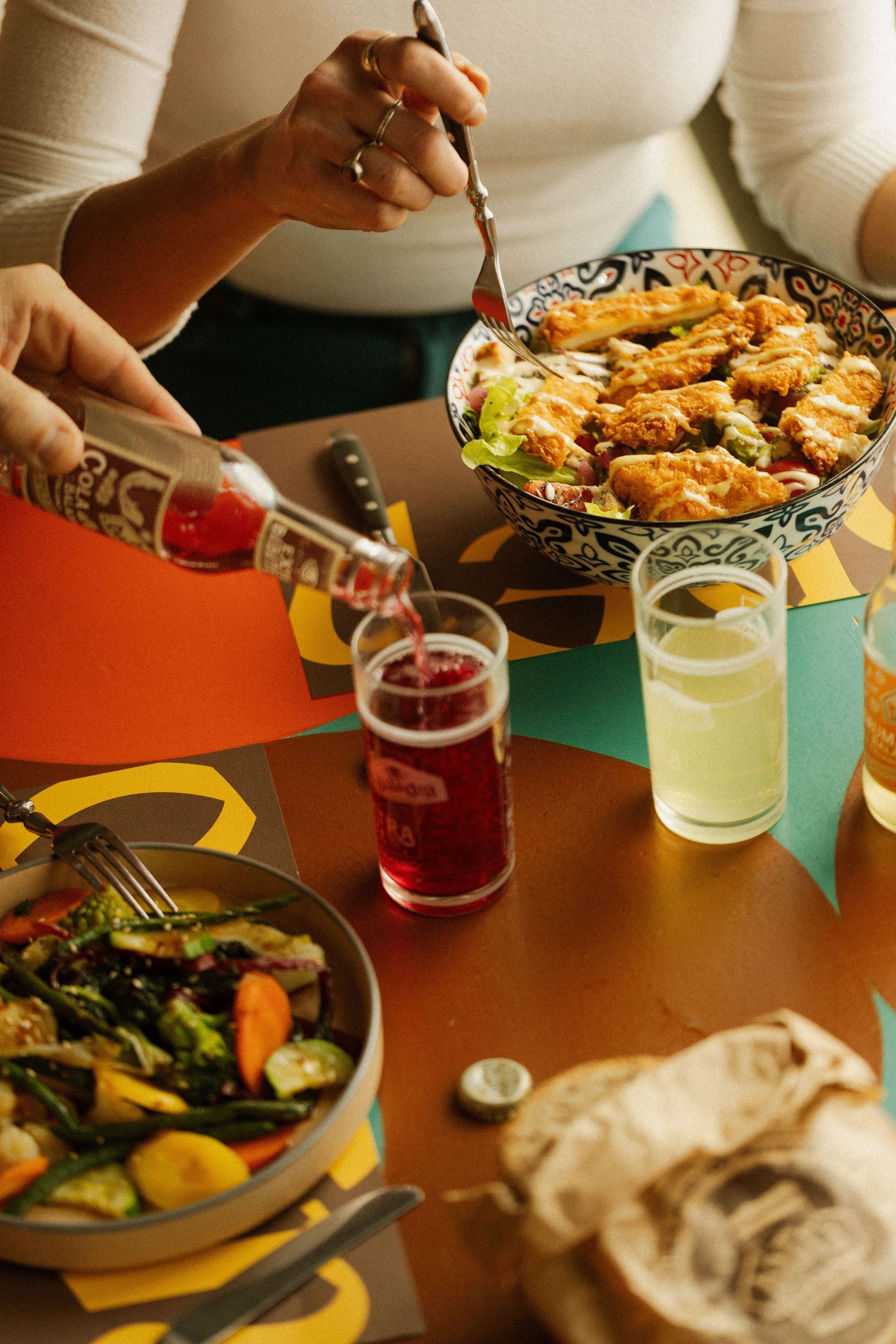 Servizio di birra artigianale e piatti con verdure e pollo impanato al ristorante Open Baladin Torino.