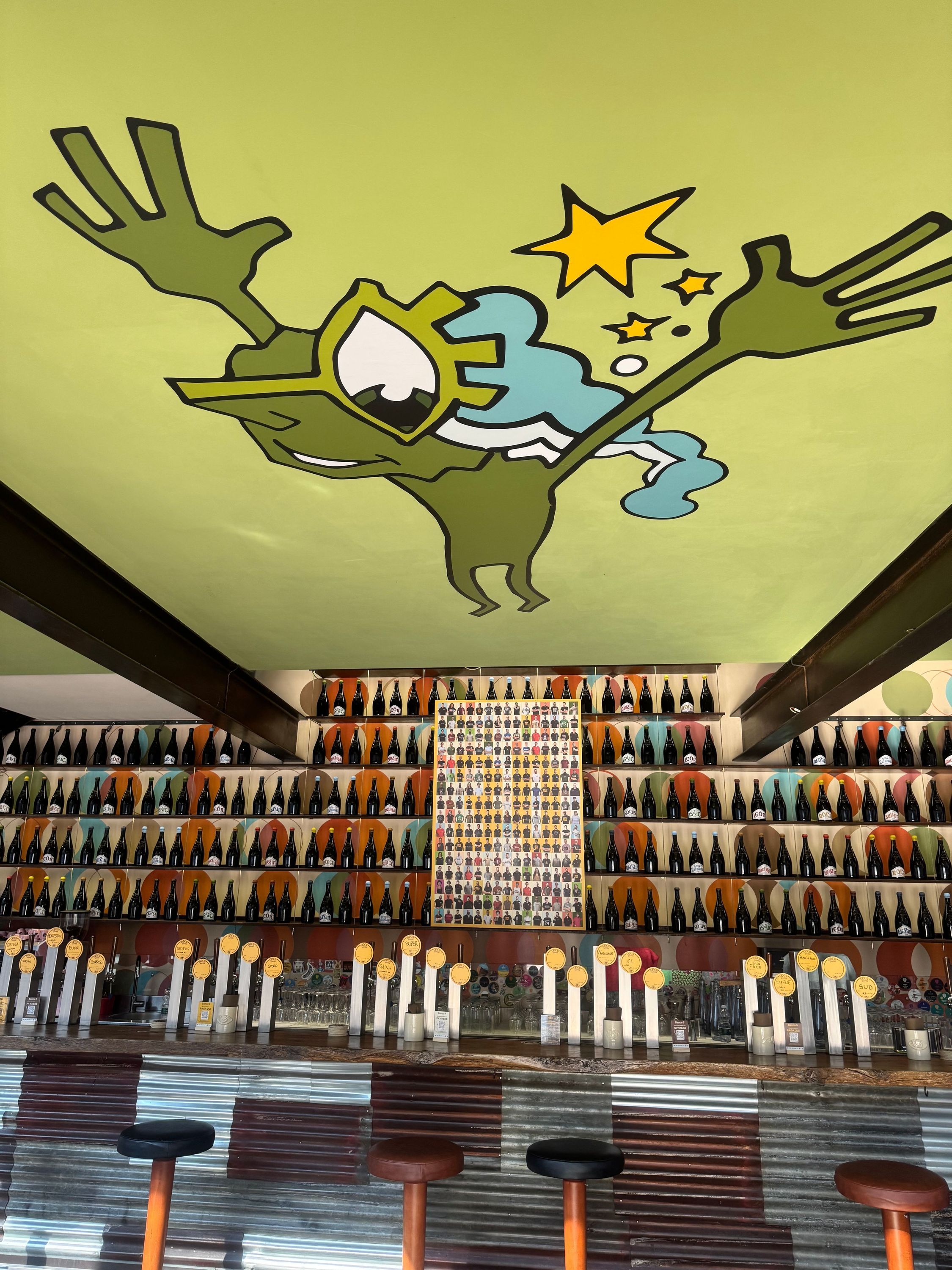 Bar avec large collection de bouteilles de bière artisanale et un plafond peint original au restaurant Open Baladin Torino.