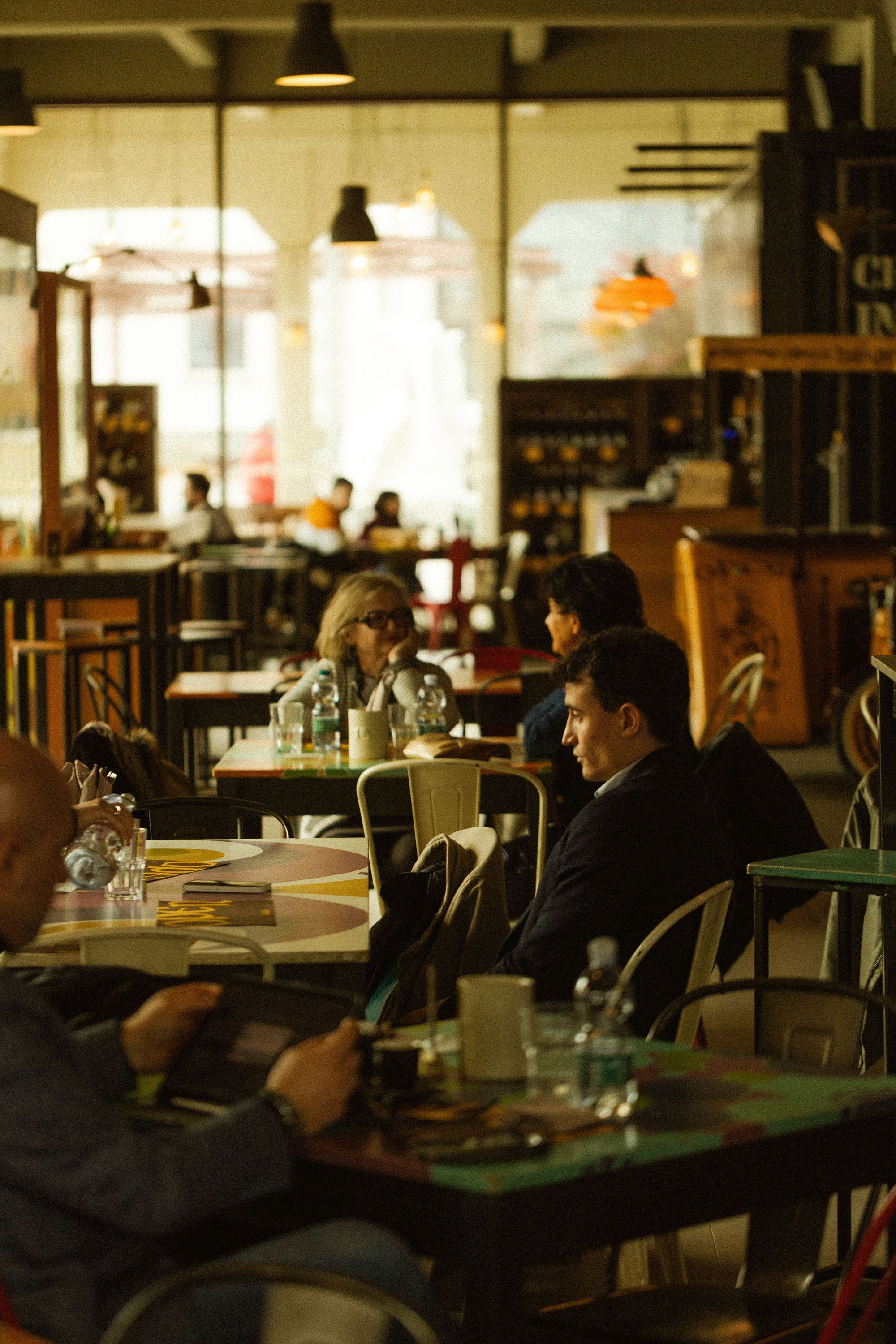 Intérieur du restaurant Open Baladin Cuneo avec des clients assis à des tables, ambiance chaleureuse et éclairage doux.