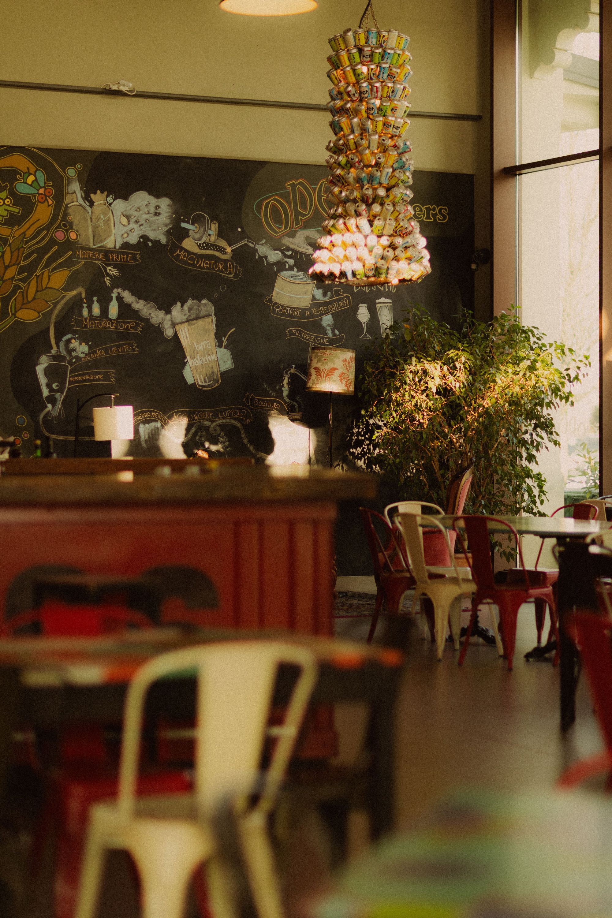 Interior of Open Baladin Cuneo with craft beer-themed wall art and a unique hanging decoration by the window seating area.